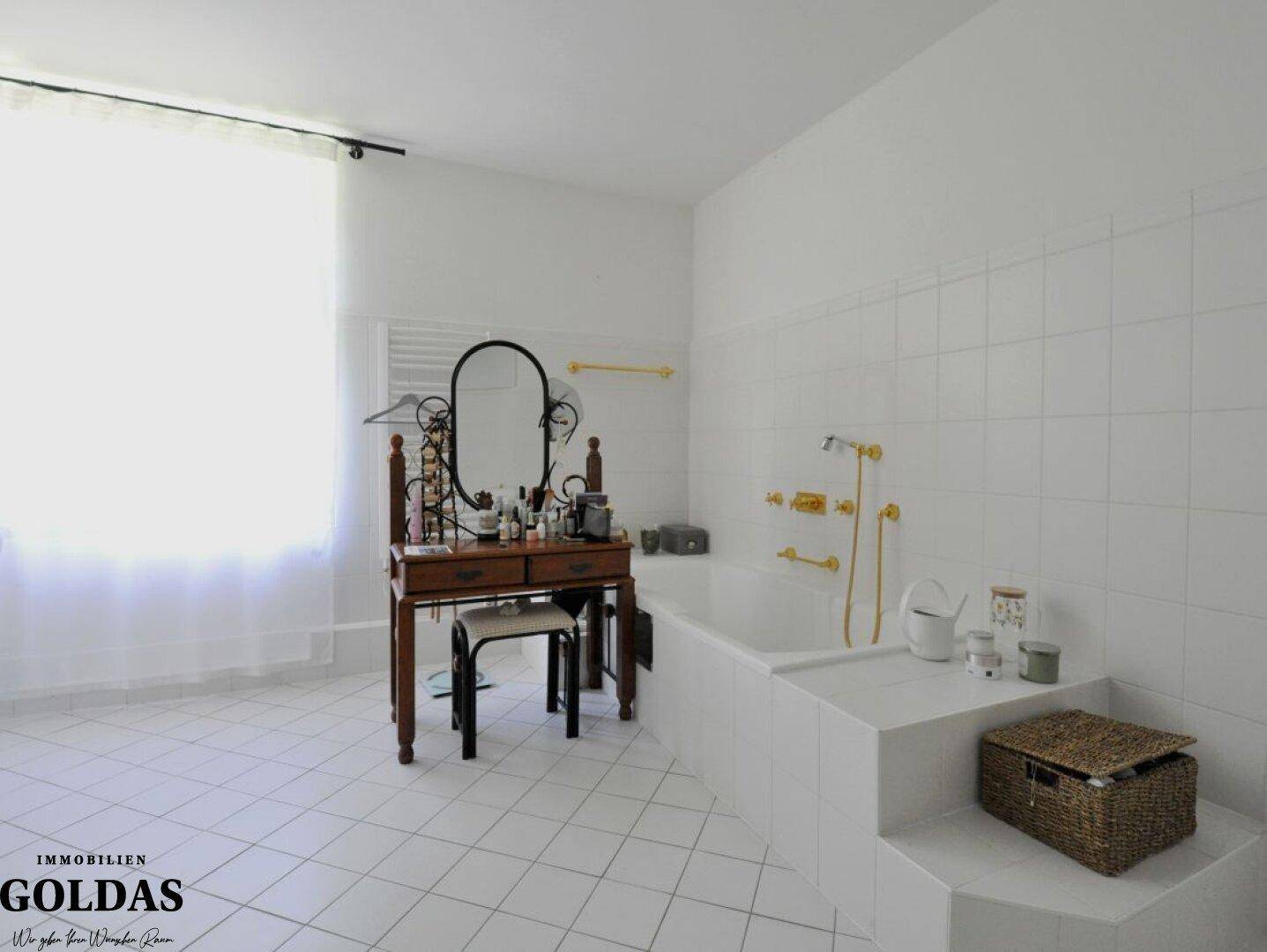 Helles Badezimmer mit weißer Badewanne, Fliesenboden und einem Fenster für Tageslicht.