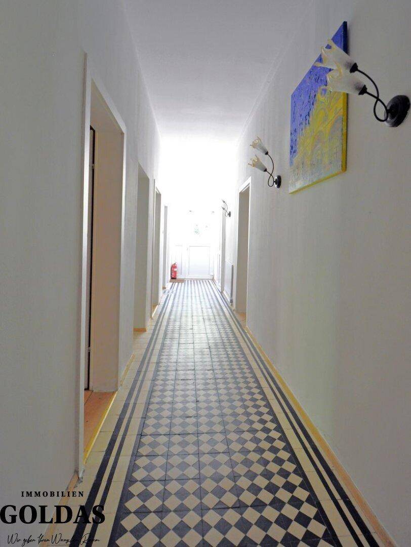 Heller Flur mit geometrischem Fliesenmuster und Türen zu verschiedenen Räumen.