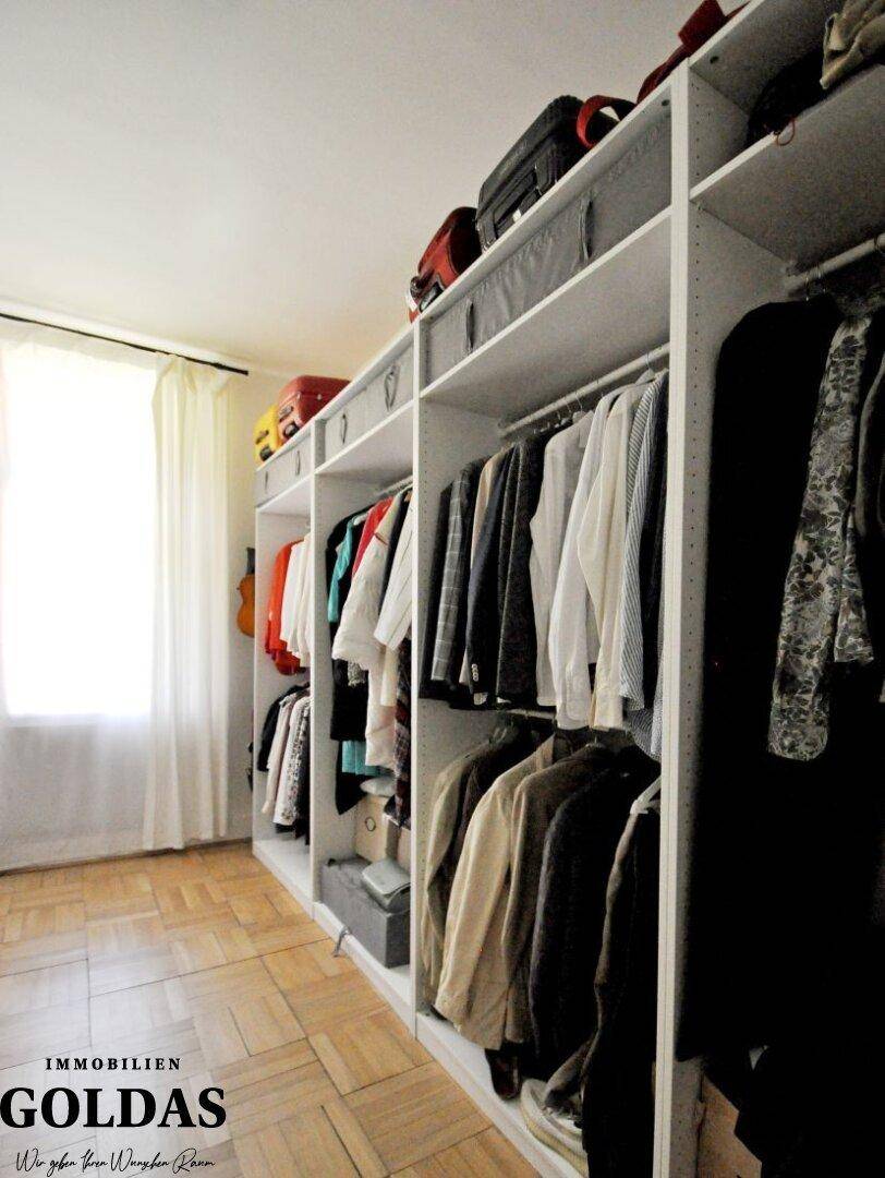 Begehbarer Kleiderschrank mit Regalen und Kleiderstangen, ausgestattet mit Parkettboden.