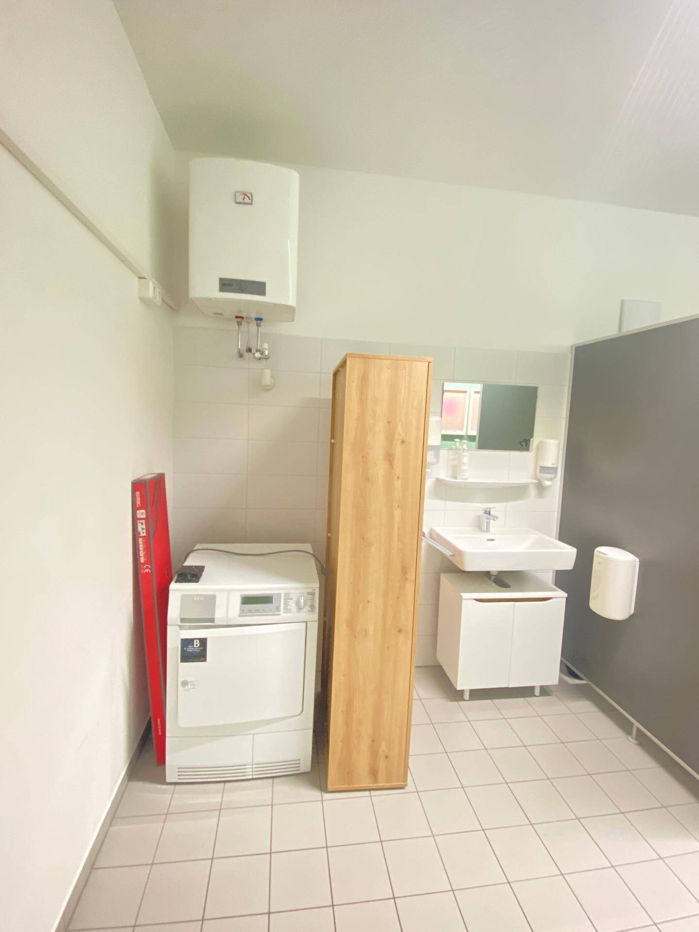 Waschraum mit Trockner, Waschbecken, Boiler und Fliesenboden.