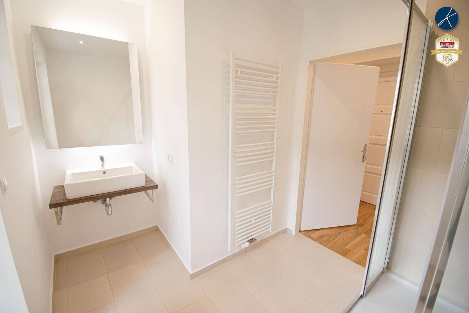 Modernes Badezimmer mit Waschbecken, Spiegel und beheiztem Handtuchhalter.