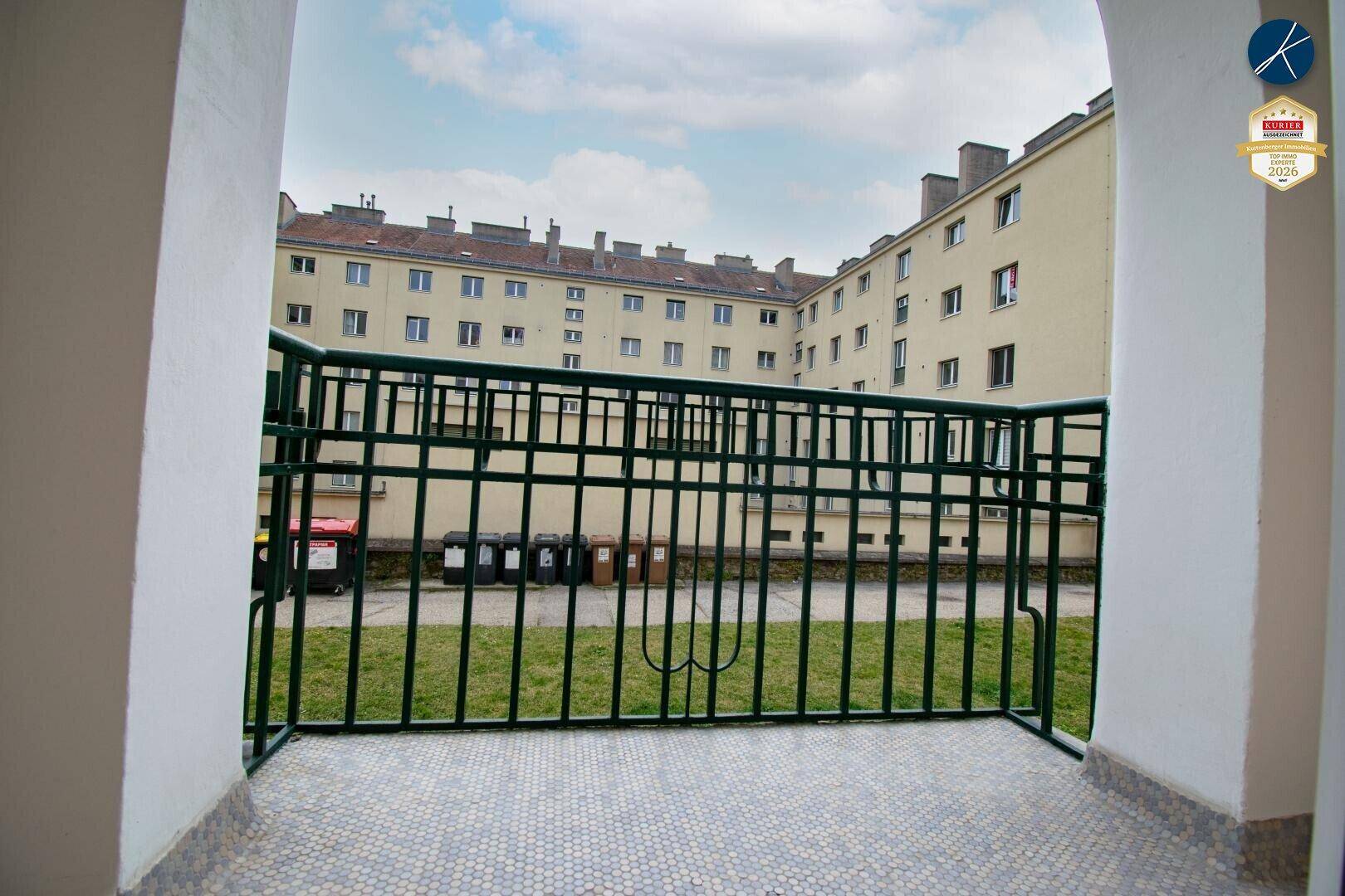 Kleiner Balkon mit Blick auf den Innenhof und die umliegenden Gebäude.