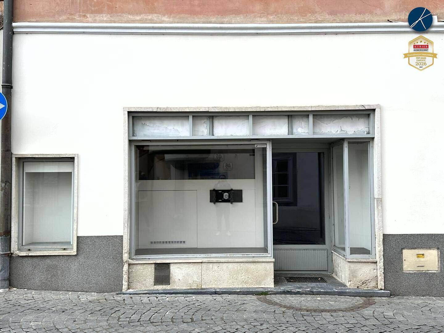 Fassade eines Geschäftsgebäudes mit großen Schaufenstern und Eingangstür, typisch für eine Ladenfront in der Stadt.