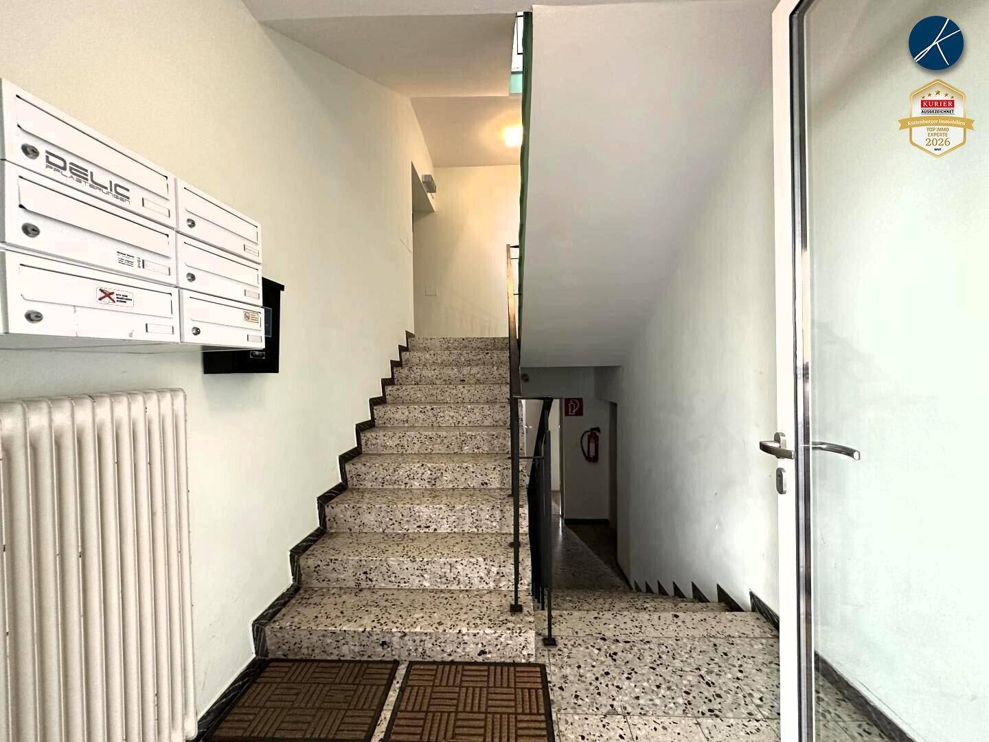 Treppenhaus mit Terrazzostufen und Briefkästen, führt zu den oberen Etagen des Gebäudes.