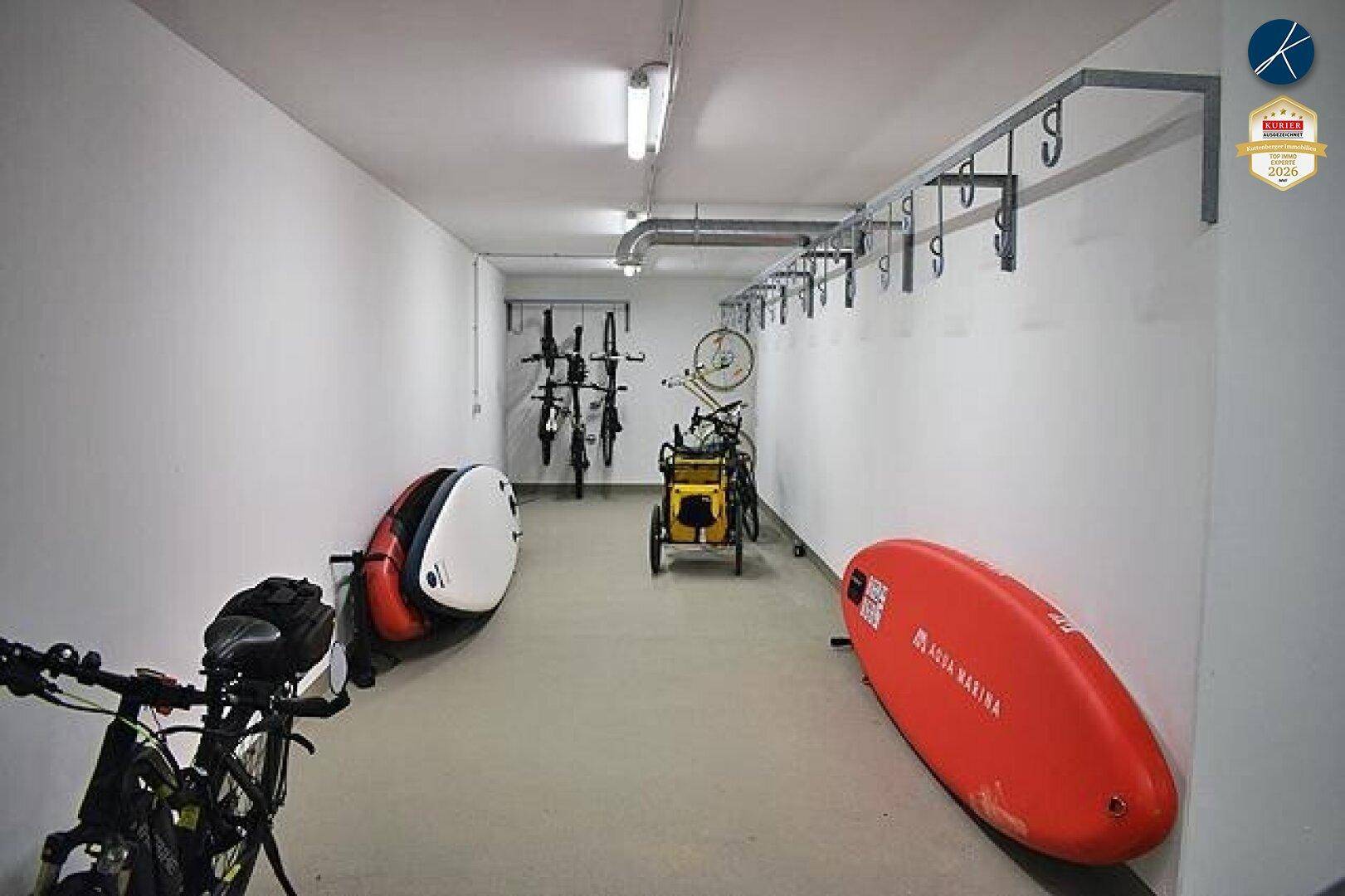 Geräumiger Abstellraum für Fahrräder und Wassersportausrüstung mit praktischen Wandhalterungen.