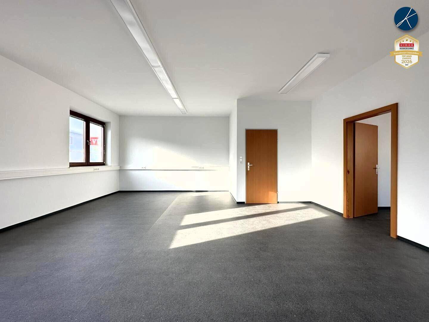 Leerer Büroraum mit zwei Holztüren und viel Tageslicht, ideal für flexible Raumgestaltung.