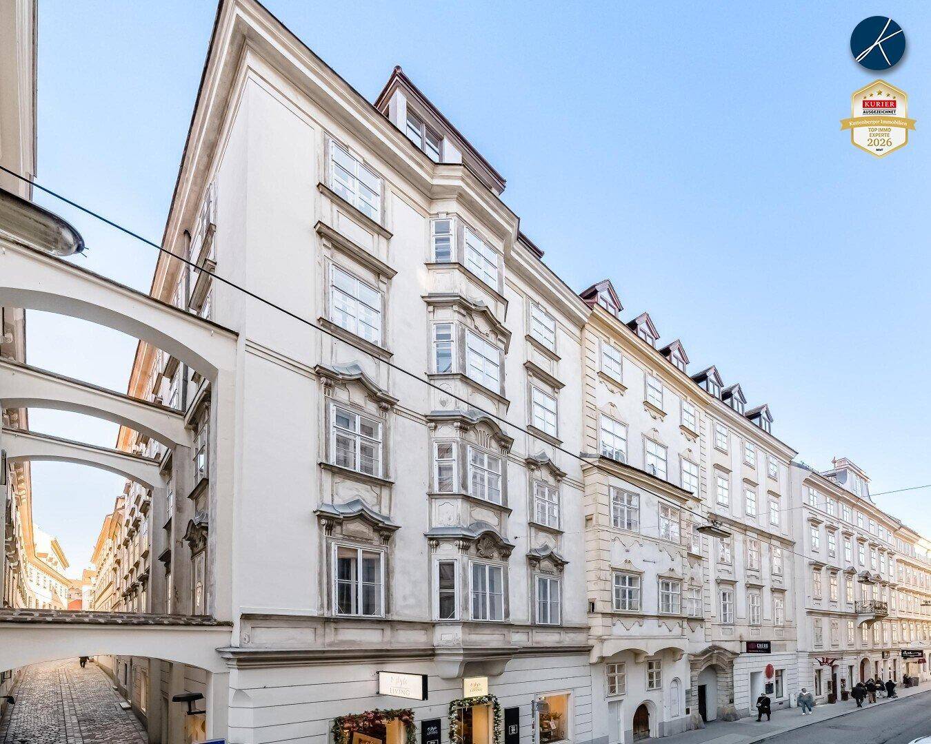 Historisches Gebäude mit eleganter Fassade, vielen Fenstern und Geschäften im Erdgeschoss.