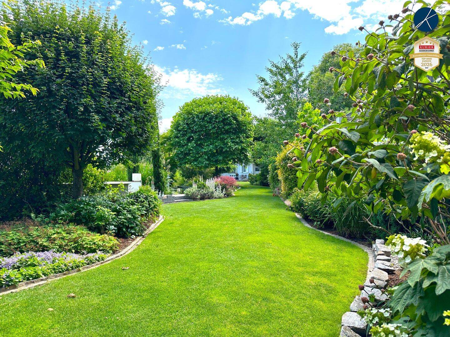 Langer, gepflegter Gartenweg mit üppiger Bepflanzung und hohen Bäumen.
