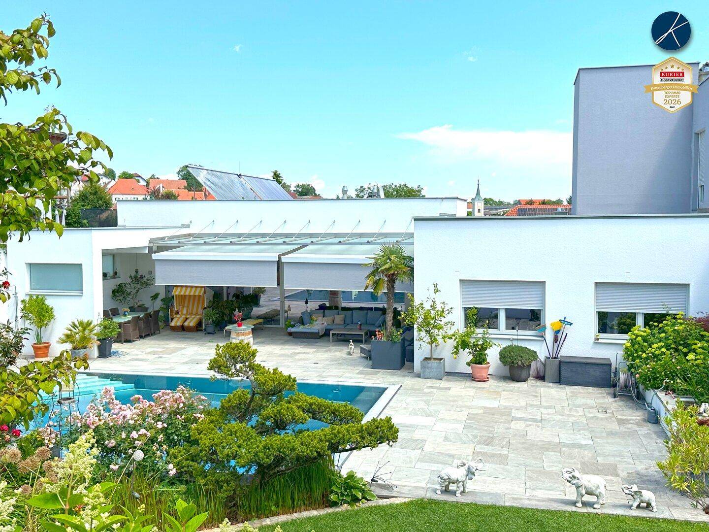 Weitläufiger Poolbereich mit moderner Architektur, gepflasterter Terrasse und Stadtblick.