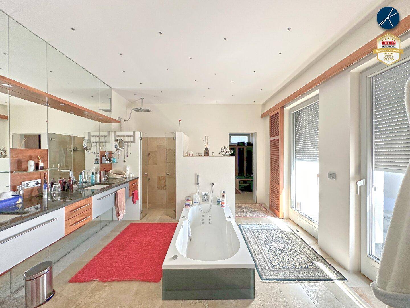 Großes Badezimmer mit Whirlpool-Badewanne, Doppelwaschbecken und Zugang zur Terrasse.