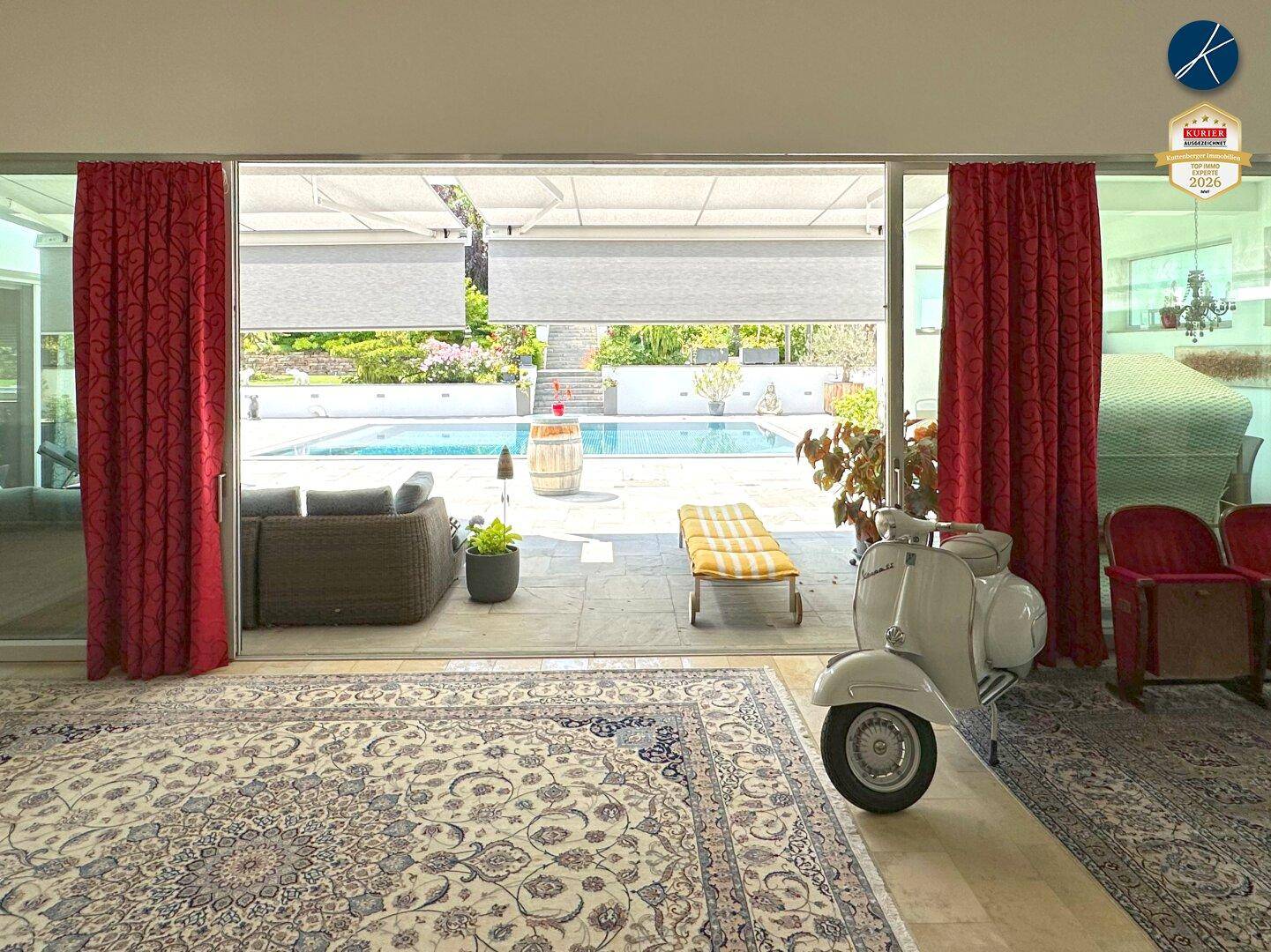 Heller Wohnbereich mit Blick auf den Pool und Zugang zur Terrasse.