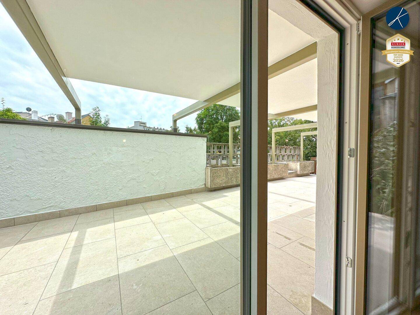 Heller Zugang zur großzügigen Terrasse durch eine breite Glastür, die viel Licht hereinlässt.