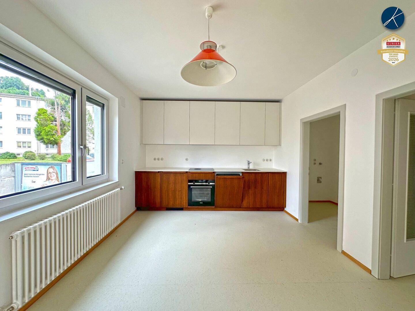 Helle Küche mit modernen Holzunterschränken, weißen Oberschränken und großem Fenster.