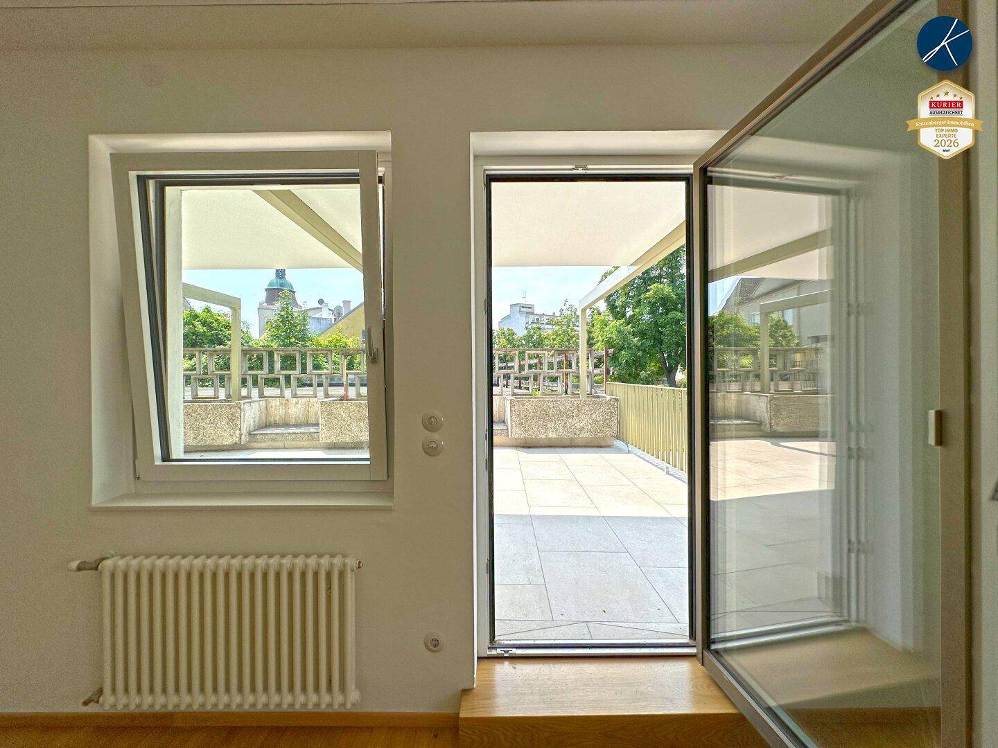 Heller Raum mit Fenster und Zugang zur Terrasse, der viel Tageslicht in den Wohnbereich bringt.