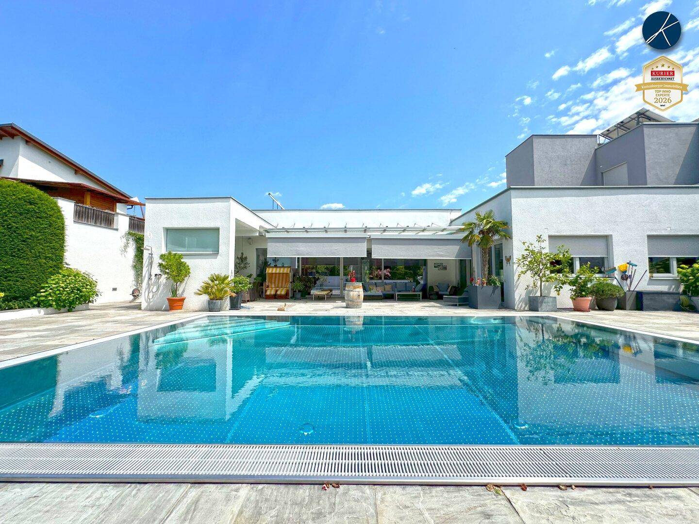 Weitläufiger Poolbereich mit moderner Architektur und sonniger Terrasse.