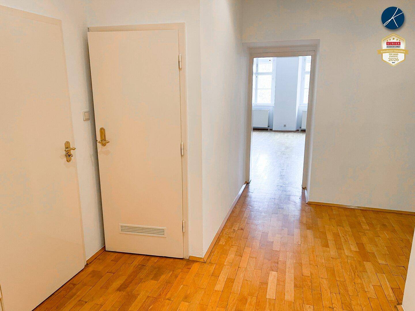 Langer Flur mit Holzboden und mehreren Türen, der verschiedene Bereiche der Wohnung verbindet.