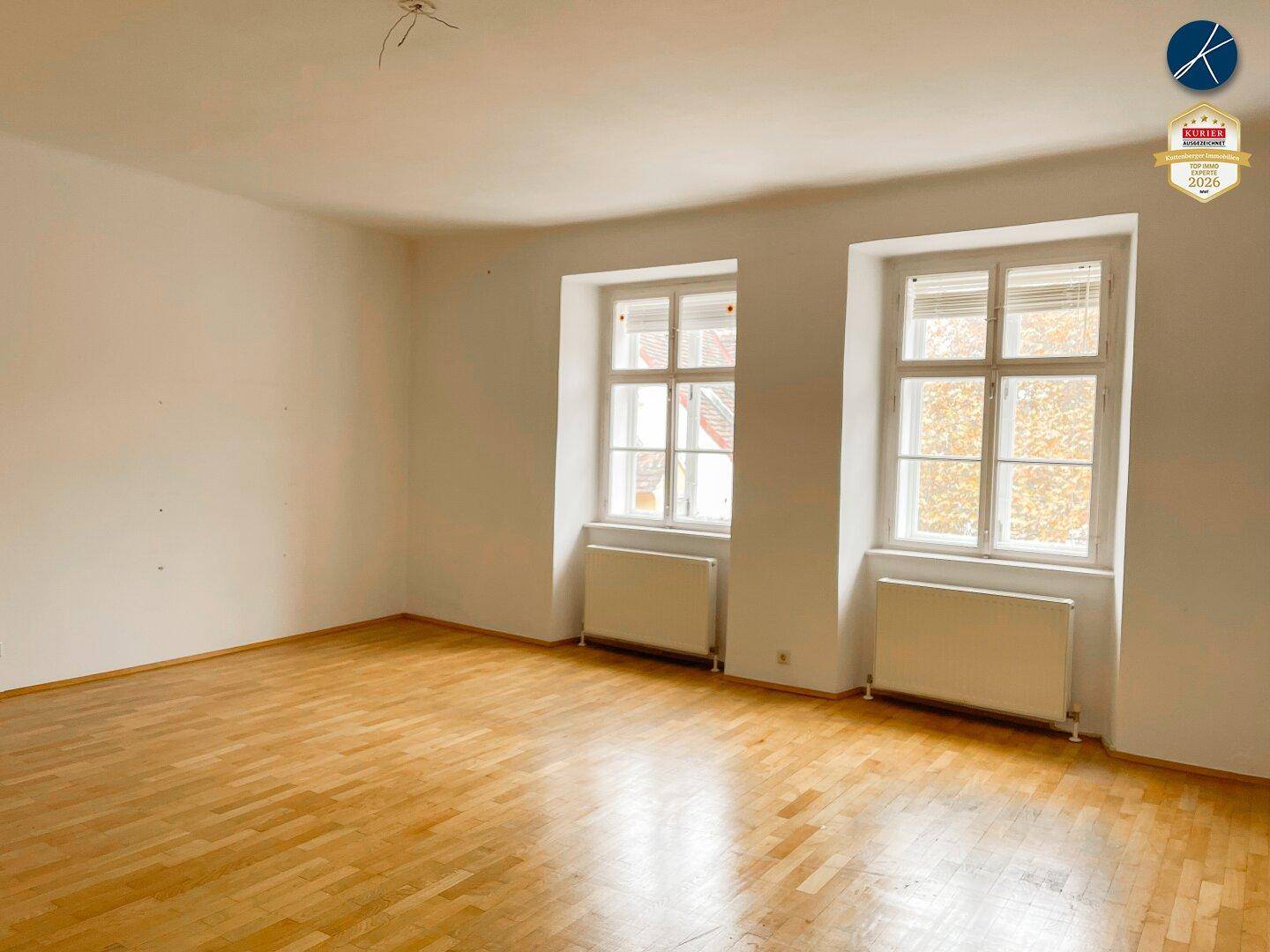 Heller Raum mit zwei großen Fenstern und Parkettboden, ideal als Wohn- oder Schlafzimmer nutzbar.