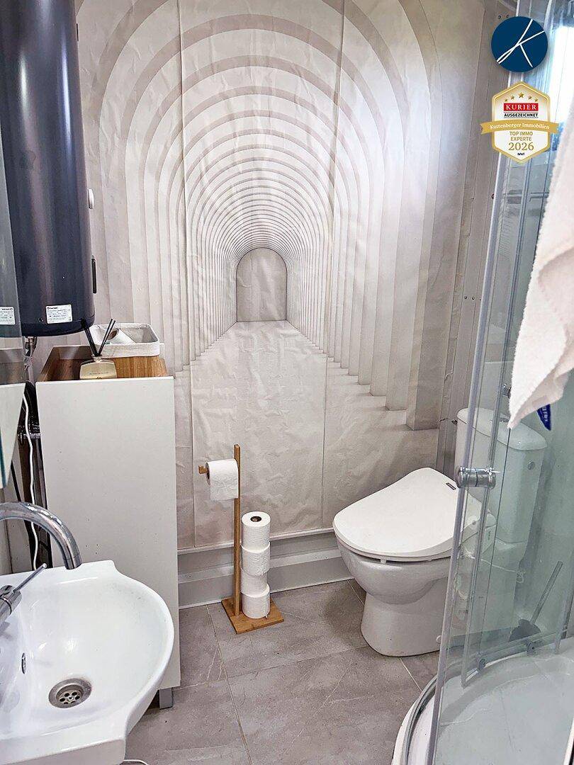 Modernes Badezimmer mit WC, Waschbecken, Dusche und einer Tapete mit optischer Tiefenwirkung.
