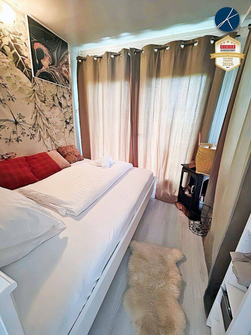 Gemütliches Schlafzimmer mit Einzelbett, floraler Tapete und blickdichten Vorhängen für Privatsphäre.