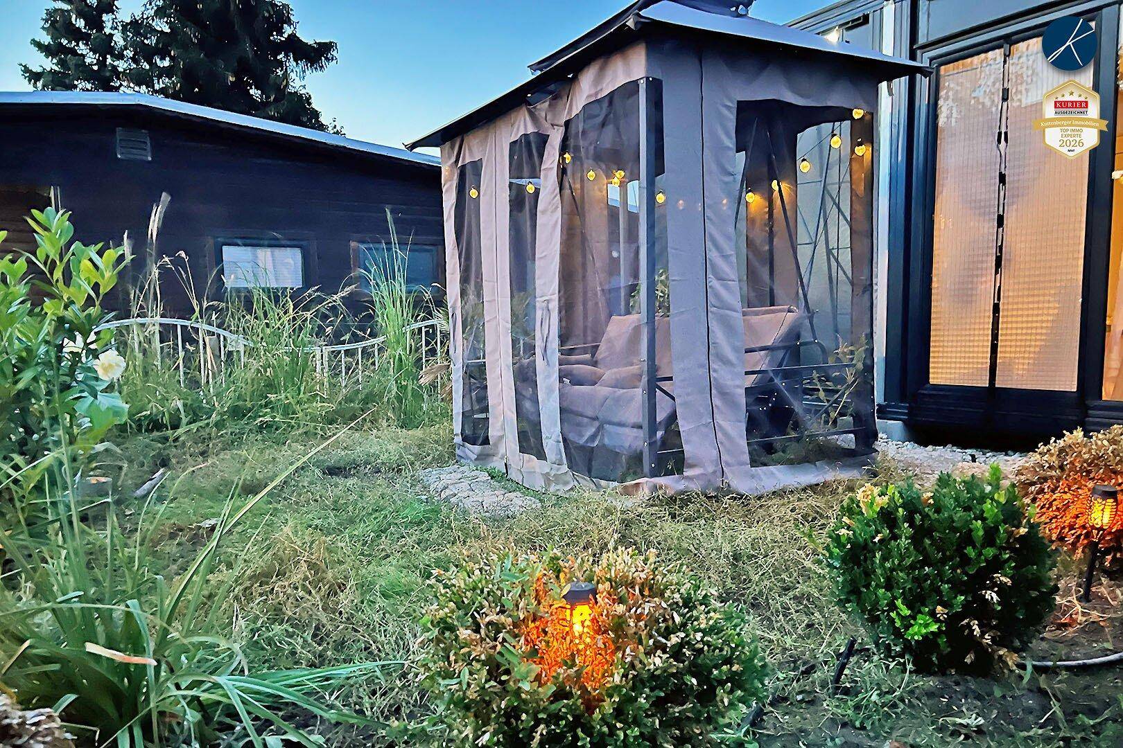 Abendliche Ansicht des Gartens mit beleuchtetem Pavillon und stimmungsvollen Solarleuchten.