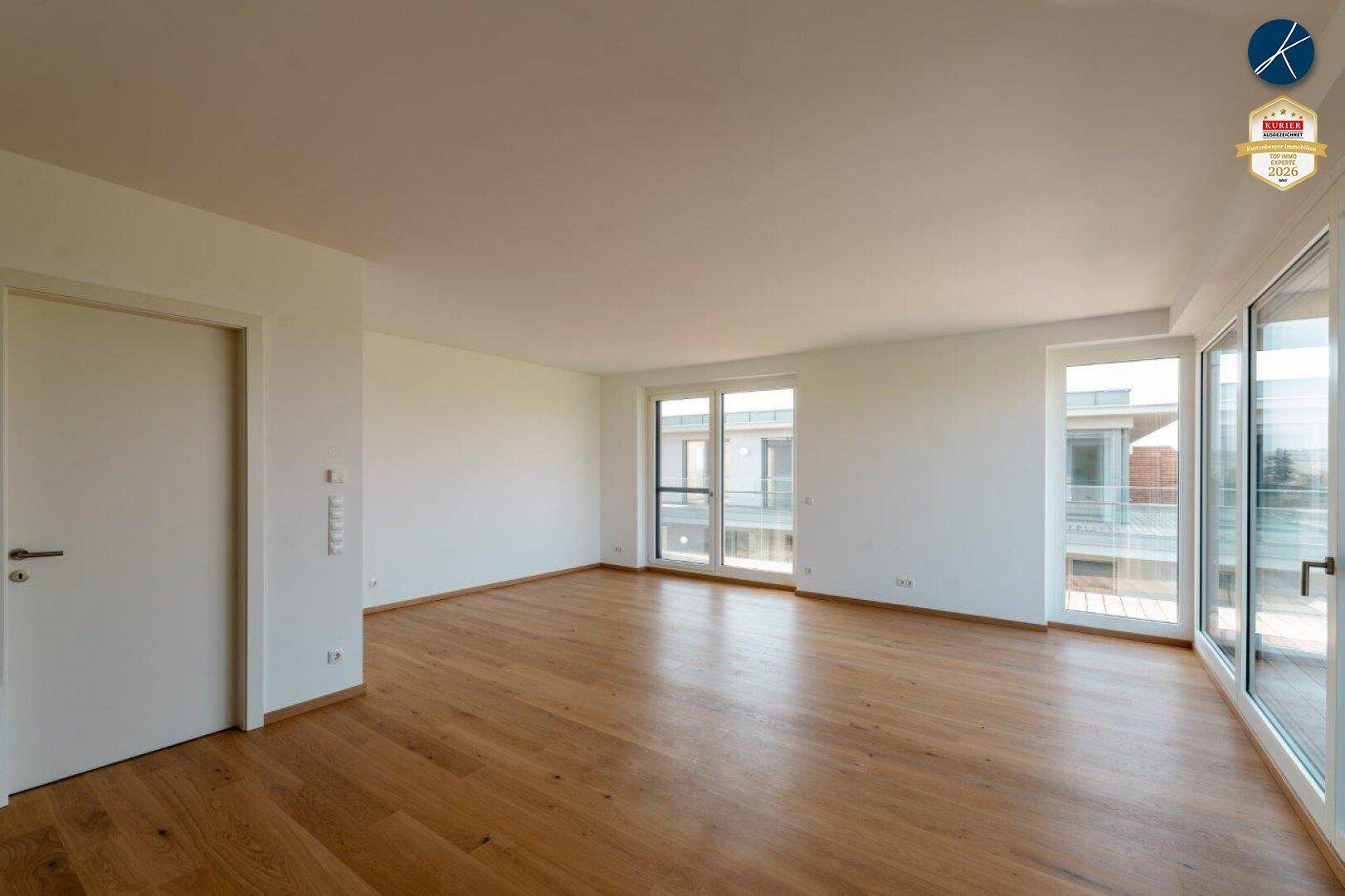 Helles, leeres Wohnzimmer mit Eichenparkettboden und großen Fenstern, die viel Tageslicht hereinlassen.