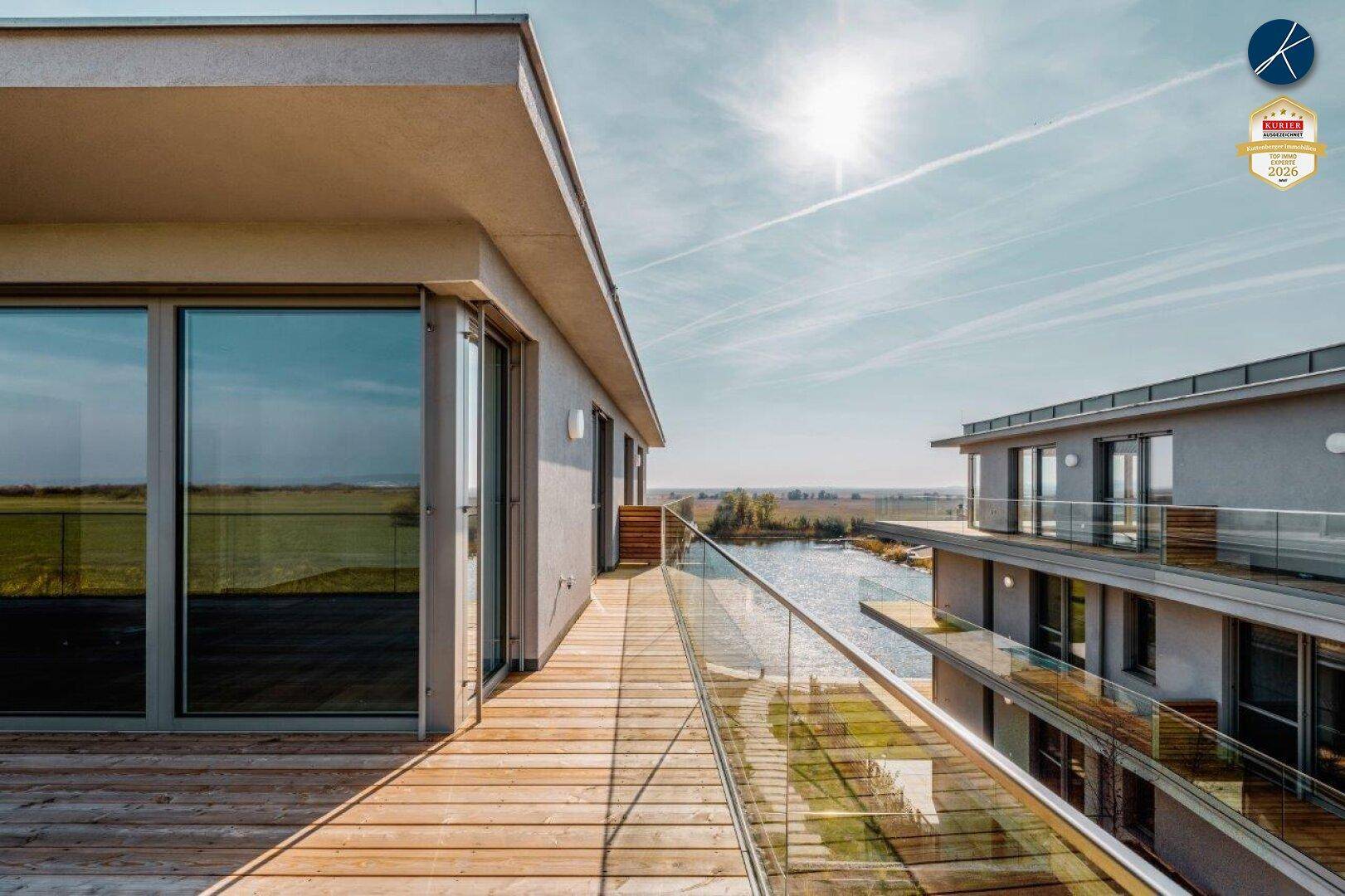 Sonnige Dachterrasse mit Glasgeländer und atemberaubendem Panoramablick auf den See und die Umgebung.
