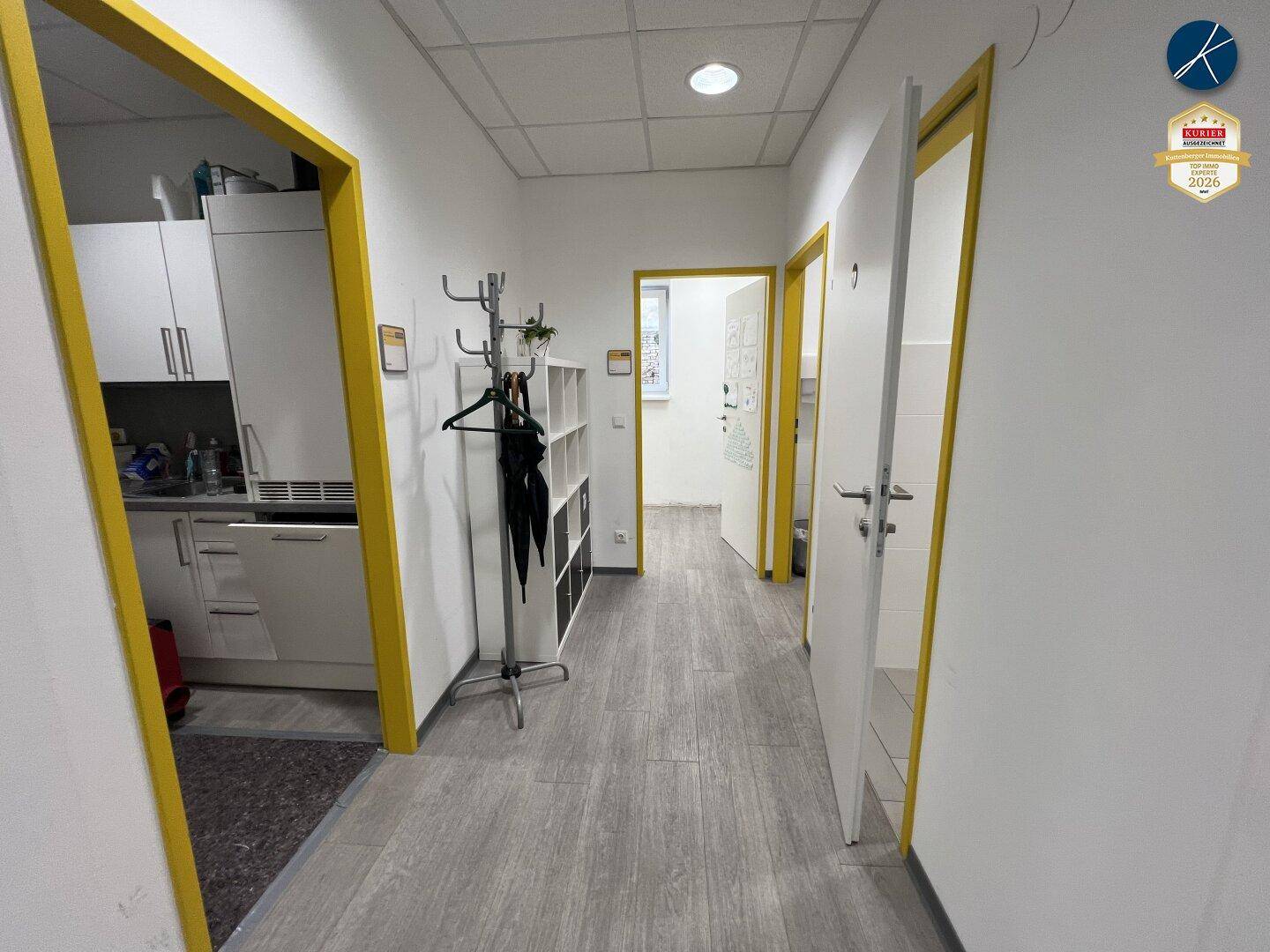 Flur mit Zugang zu einer Teeküche und weiteren Räumen, ausgestattet mit Garderobe.