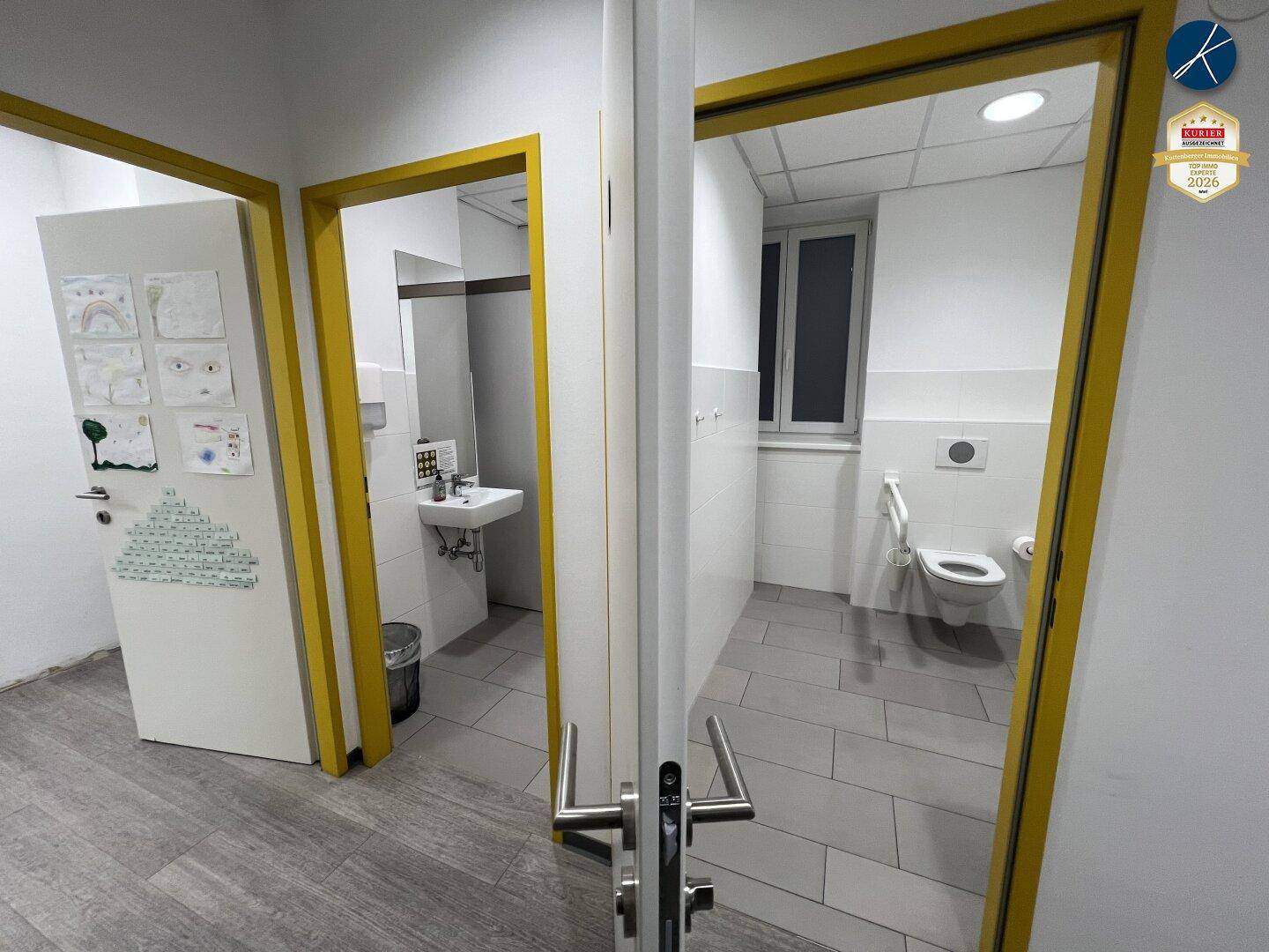 Zwei Badezimmerzugänge, einer davon barrierefrei mit Haltegriffen und modernem Design.