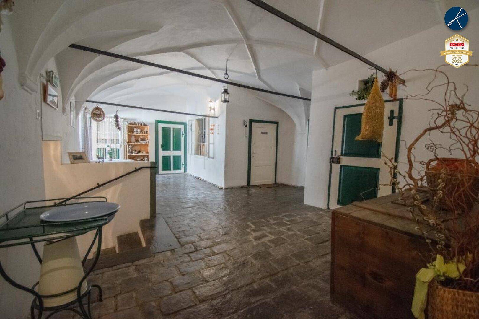 Historischer Innenraum mit beeindruckenden Kreuzgewölbedecken, Steinboden und traditionellen grünen Türen.