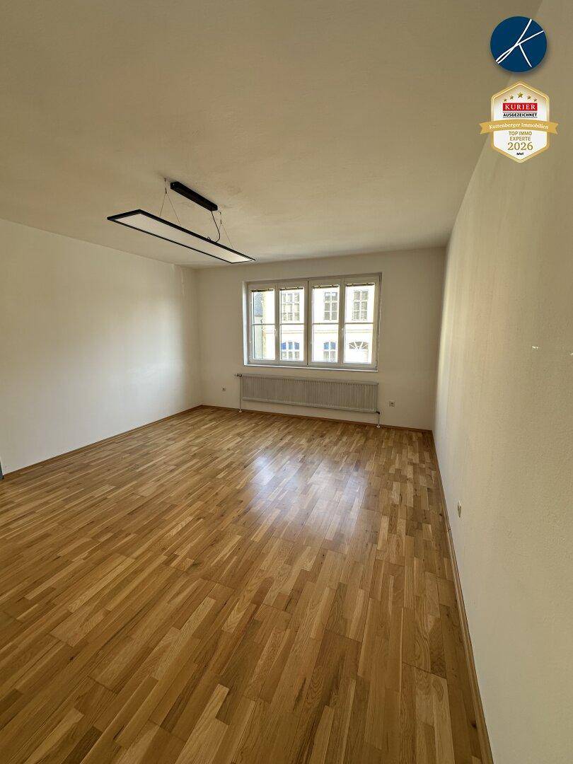 Helles, leeres Zimmer mit Parkettboden und Fenster, ideal als Schlaf- oder Arbeitszimmer.