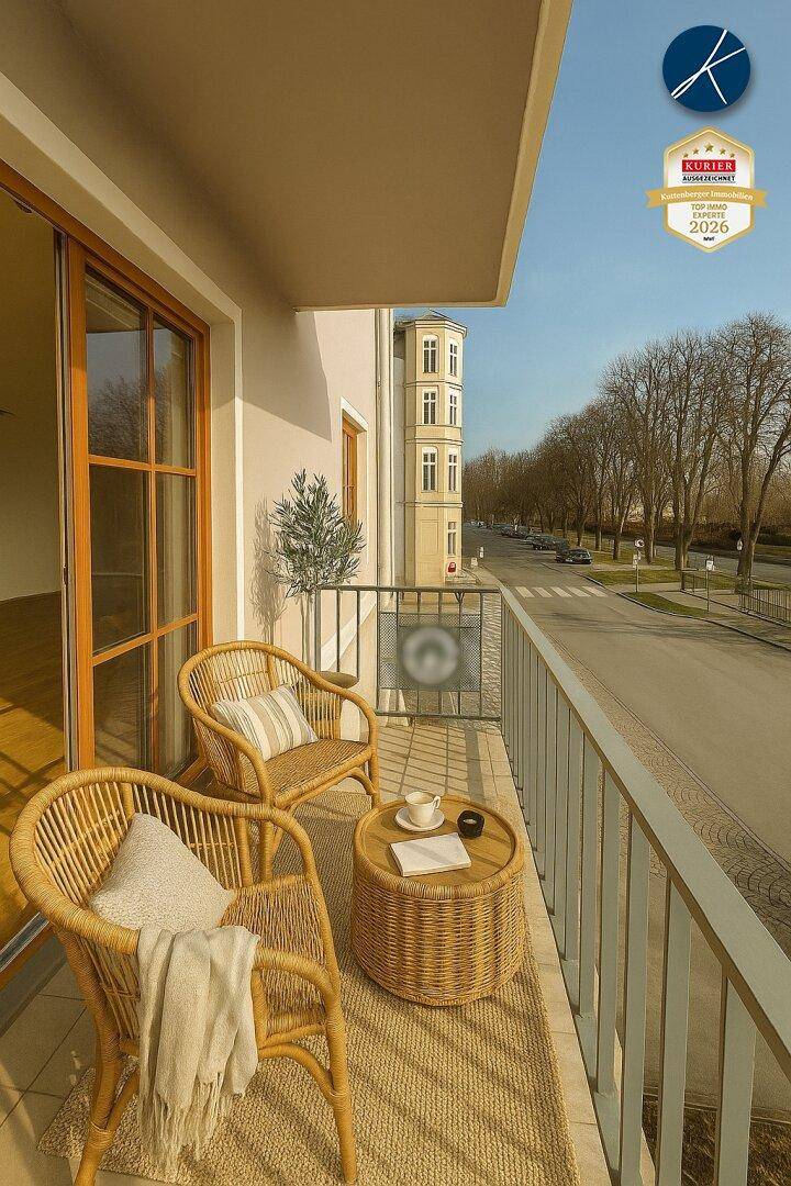 Möblierter Balkon mit Korbsesseln und Blick auf die Straße und umliegende Gebäude.
