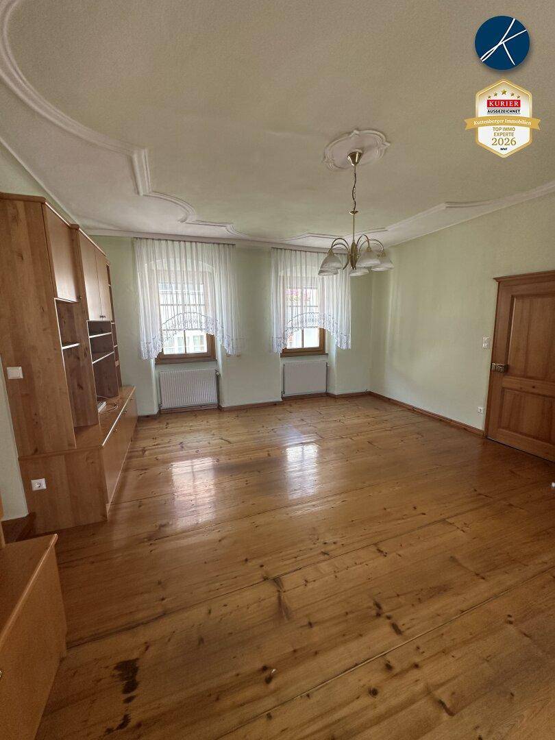 Geräumiges Wohnzimmer mit Holzboden, Stuckdecke und traditionellen Holzmöbeln.