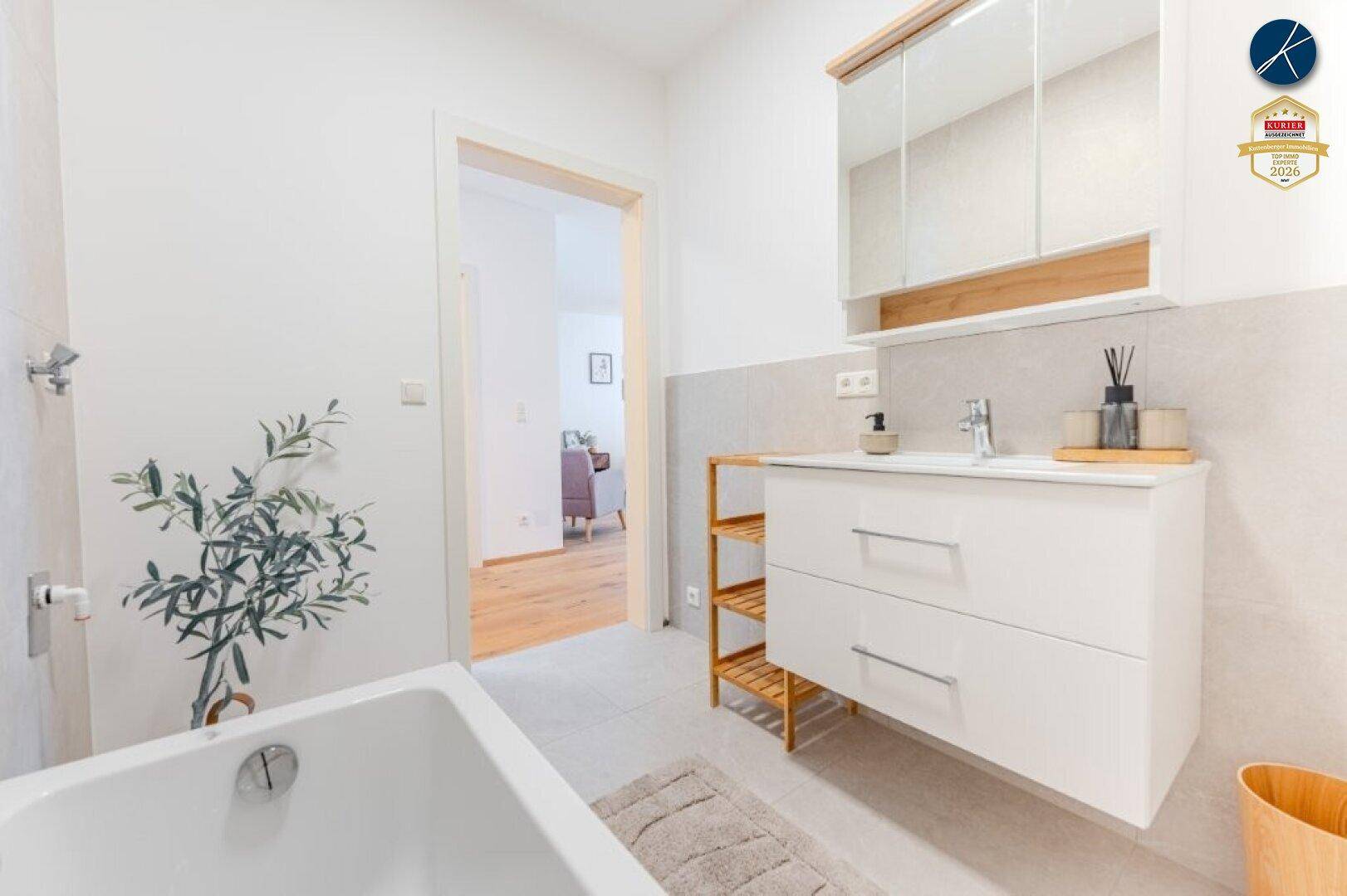Modernes Badezimmer mit Badewanne, Waschtisch und Spiegelschrank in hellen Farbtönen.