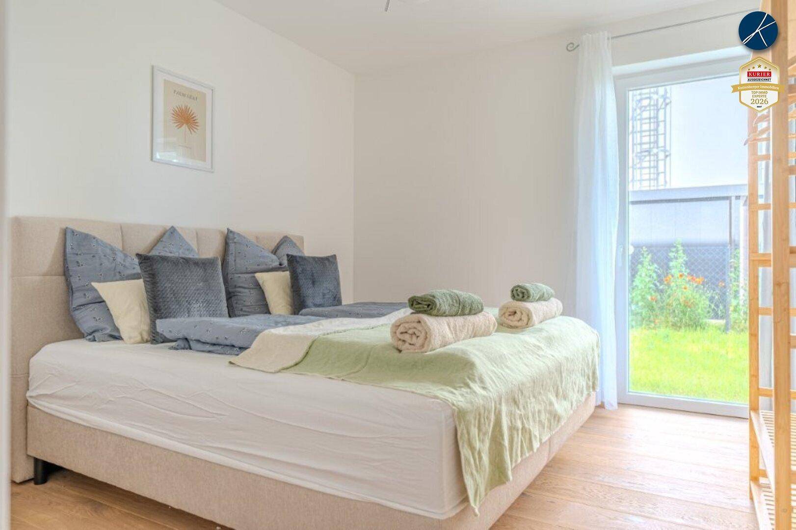 Helles Schlafzimmer mit Doppelbett, Holzboden und direktem Zugang zum Garten.