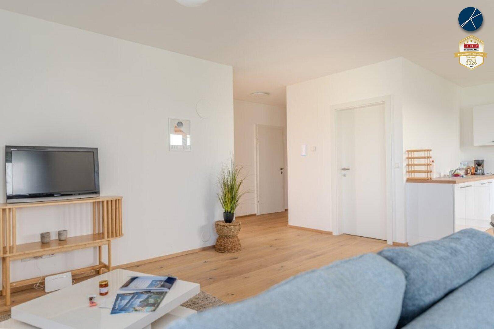 Gemütlicher Wohnbereich mit hellem Holzboden, Sofa und Blick auf den Flur.