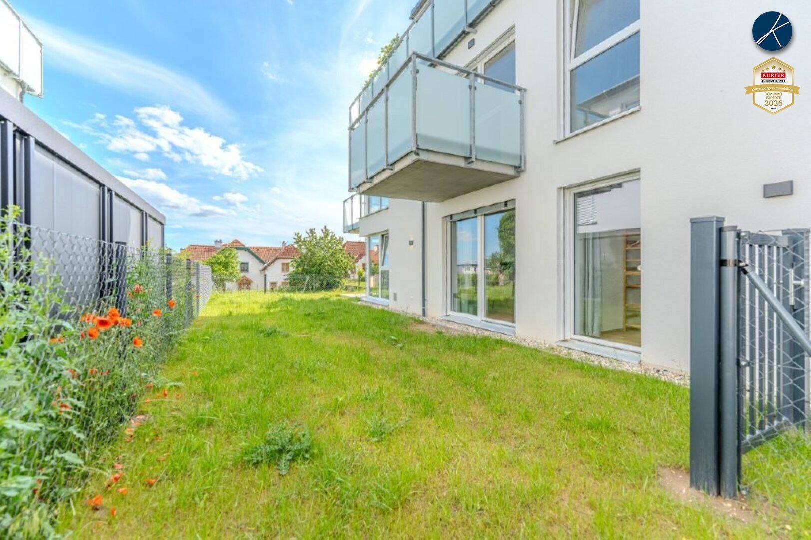 Gepflegter Gartenbereich mit Rasenfläche und Blick auf das moderne Gebäude.