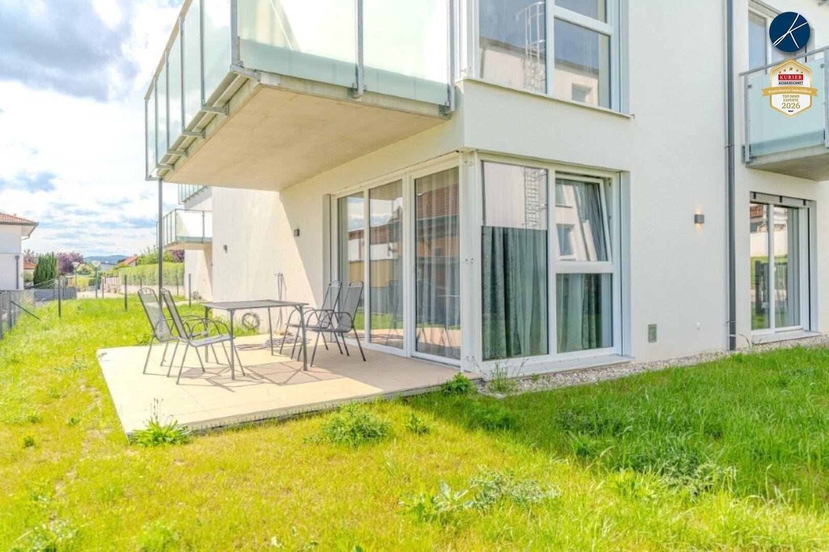 Sonniger Terrassenbereich mit Gartenmöbeln und direktem Zugang zum Rasen.