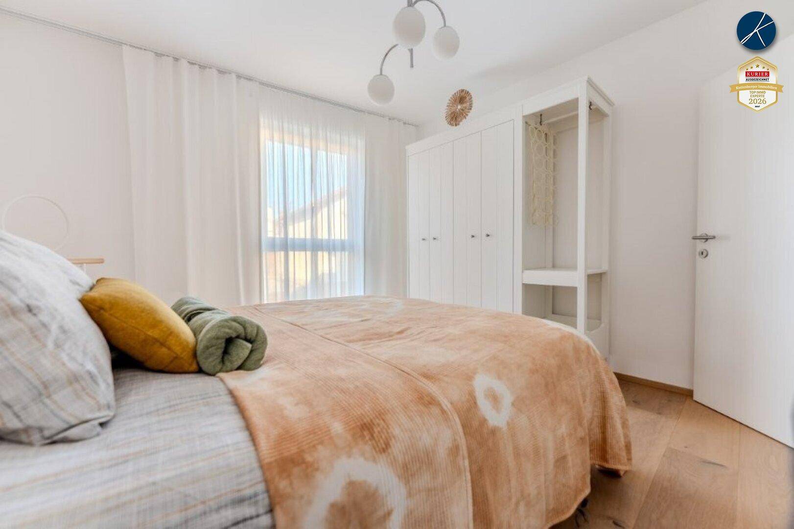 Schlafzimmer mit weißem Kleiderschrank, Doppelbett und hellem Holzboden.