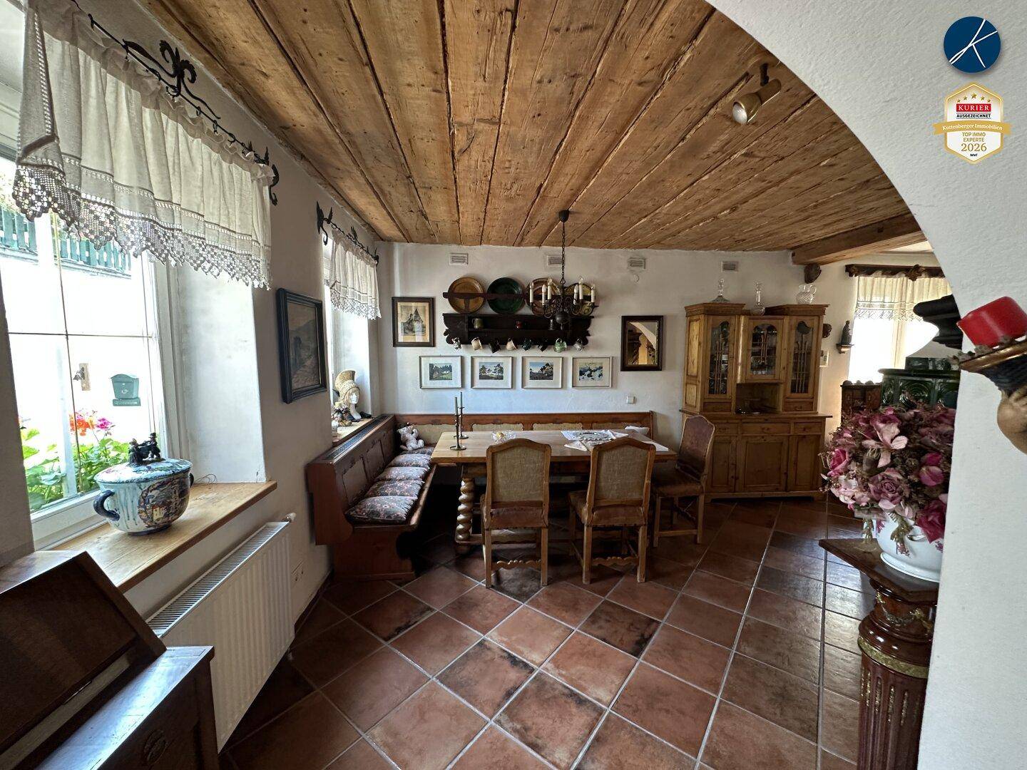 Gemütlicher Essbereich mit Holzbalkendecke, Eckbank und traditionellen Dekorationen in warmem Licht.