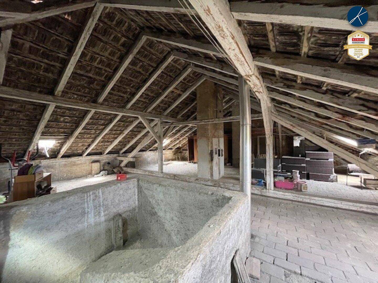Geräumiger, unfertiger Dachboden mit sichtbaren Holzbalken und Dachkonstruktion, bereit zum Ausbau.