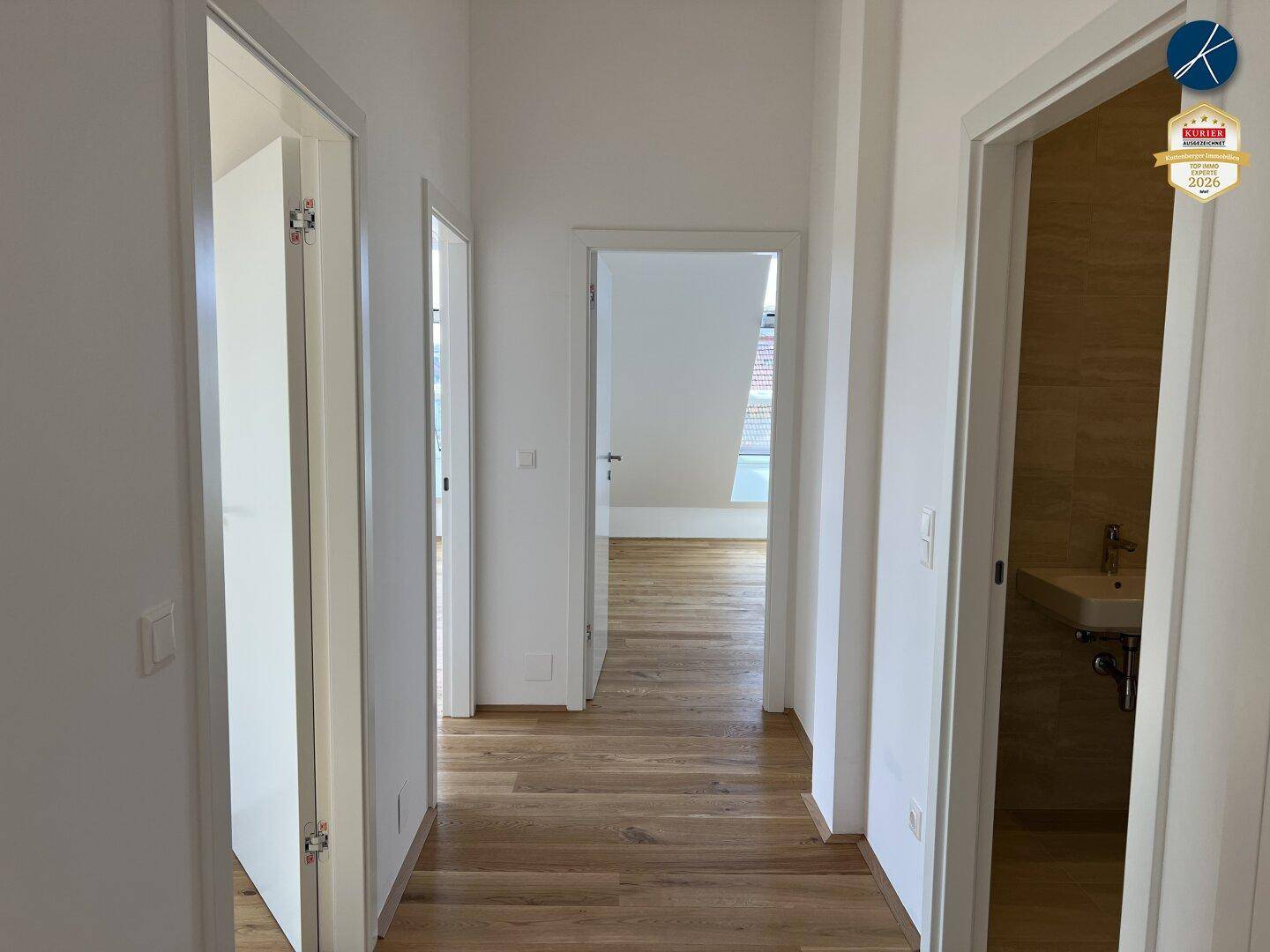 Heller Flur mit Holzboden und mehreren Türen, die zu den angrenzenden Räumen führen.