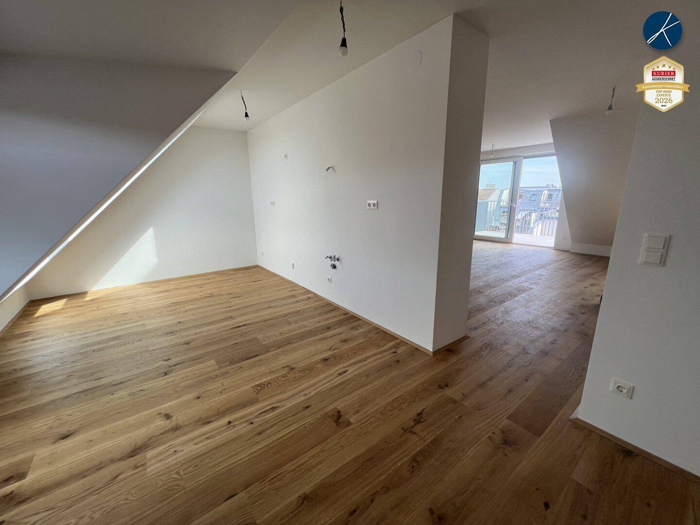 Heller Wohnbereich mit Holzboden, Dachschrägen und weitem Blick durch große Fenster.