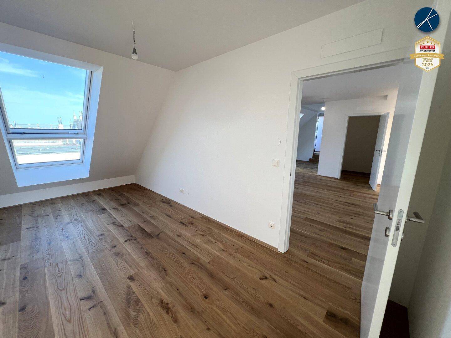 Heller Raum mit Holzboden, Dachschräge und einem großen Dachfenster für viel Licht.