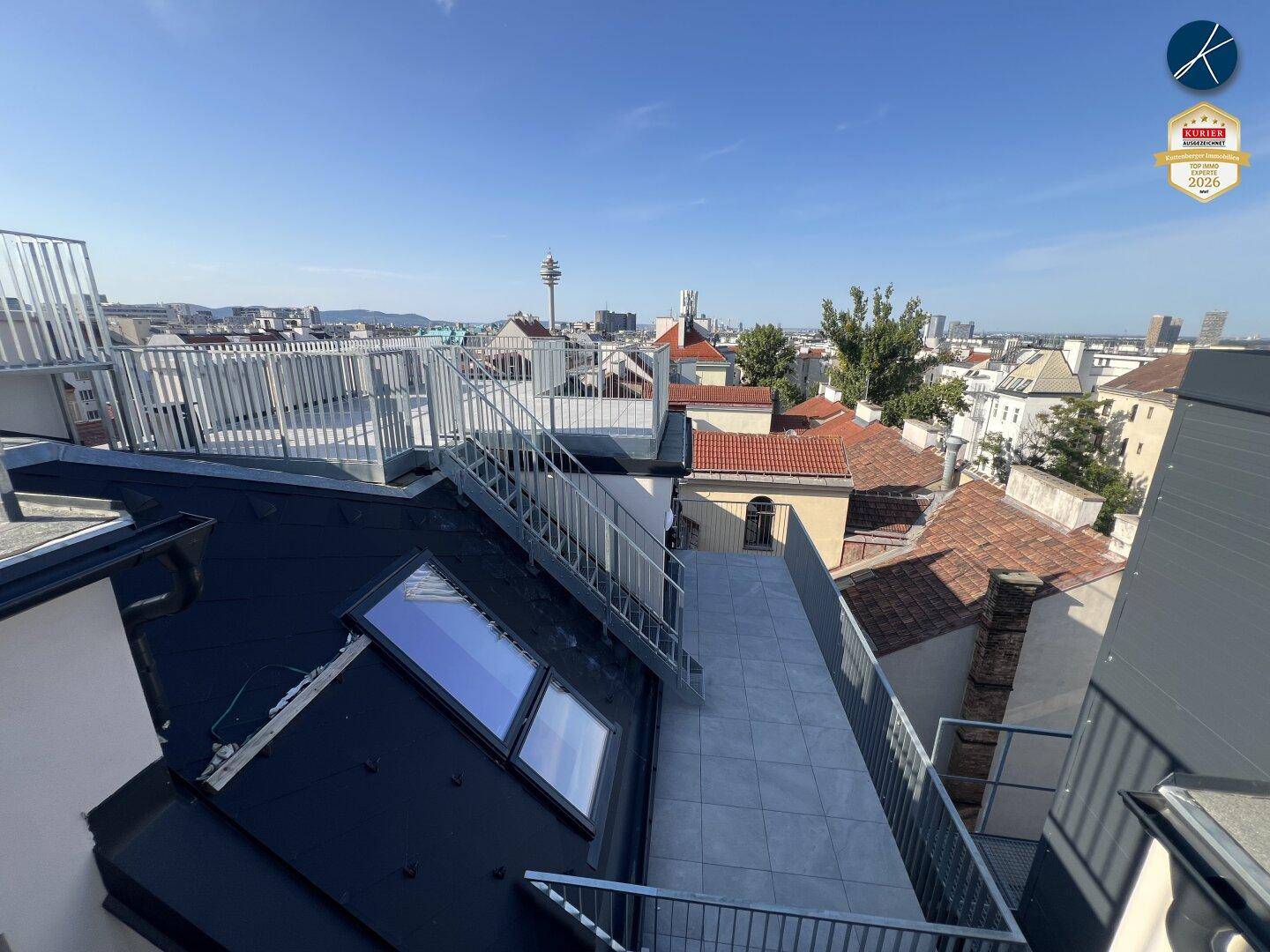 Dachterrasse mit Metallgeländer und Treppen, die einen weiten Blick über die Stadt bietet.