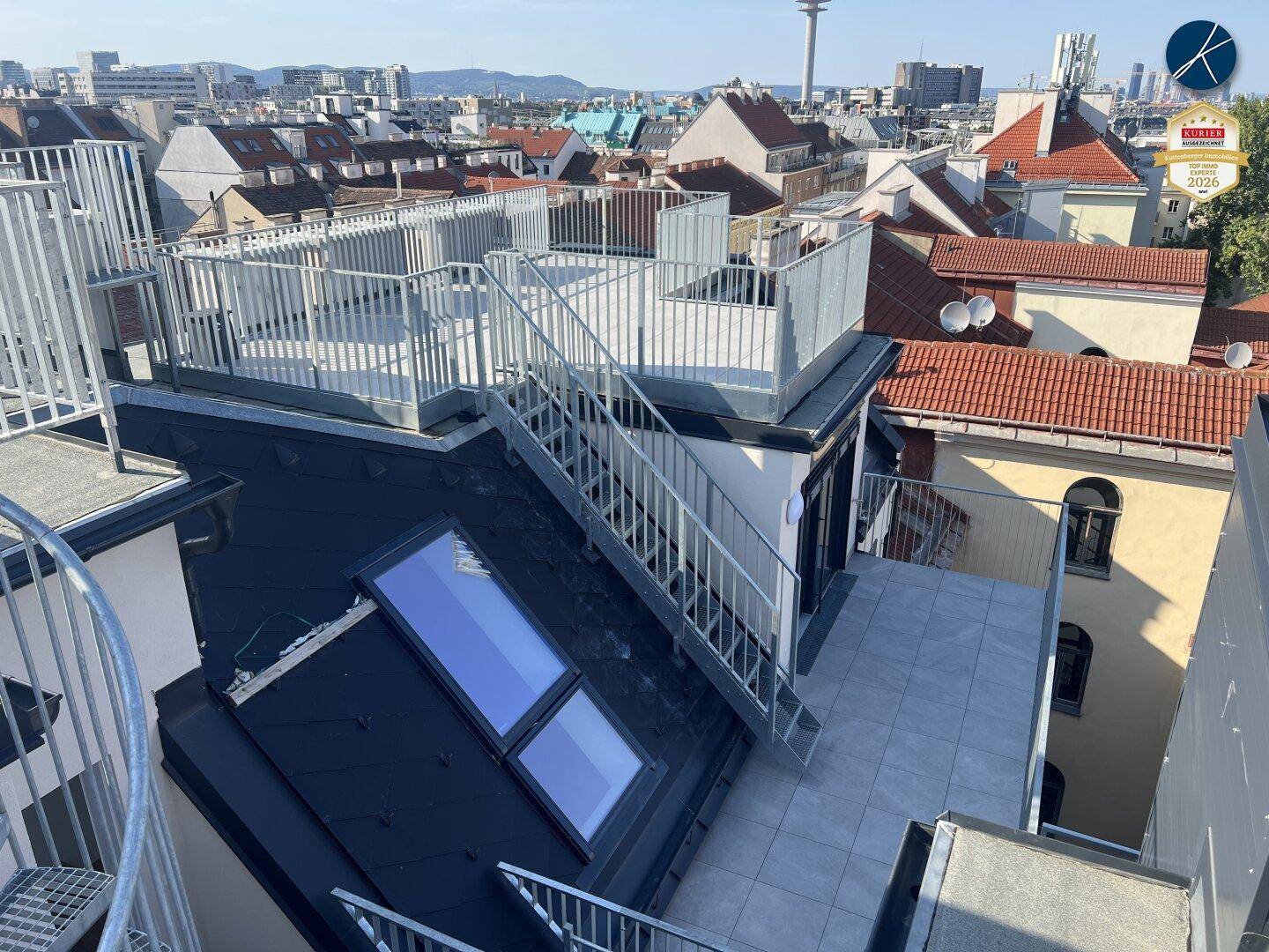 Dachbereich mit Treppenaufgang zu einer weiteren Terrasse und Blick über die Stadt.