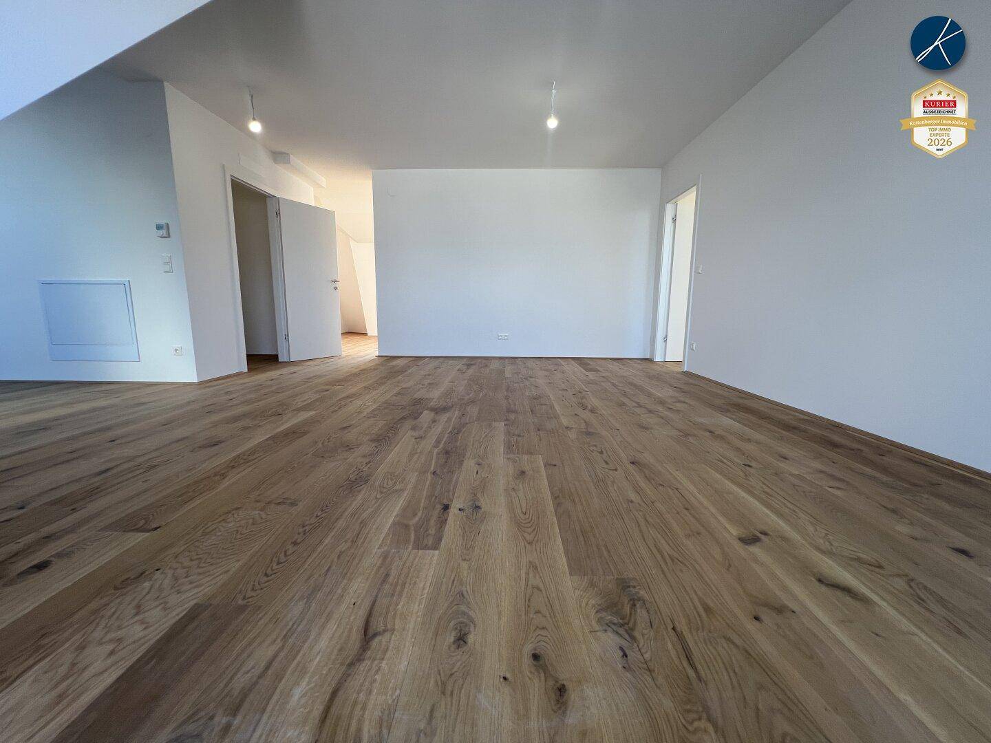 Geräumiger, heller Raum mit Holzboden und weißen Wänden, bereit zur individuellen Gestaltung.
