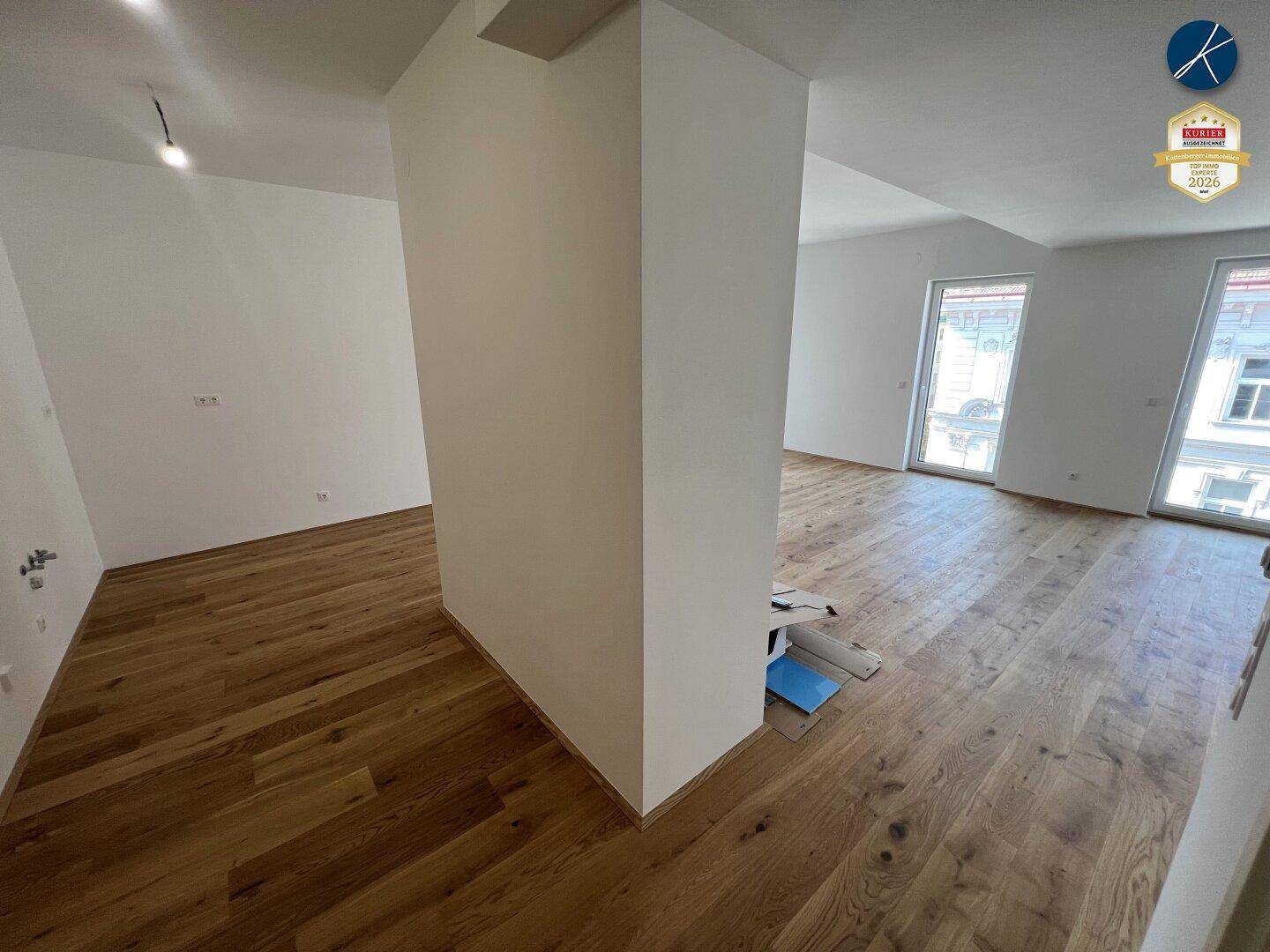 Geräumiges, leeres Zimmer mit Eichenparkettboden und großen Fenstern, die viel Tageslicht hereinlassen.