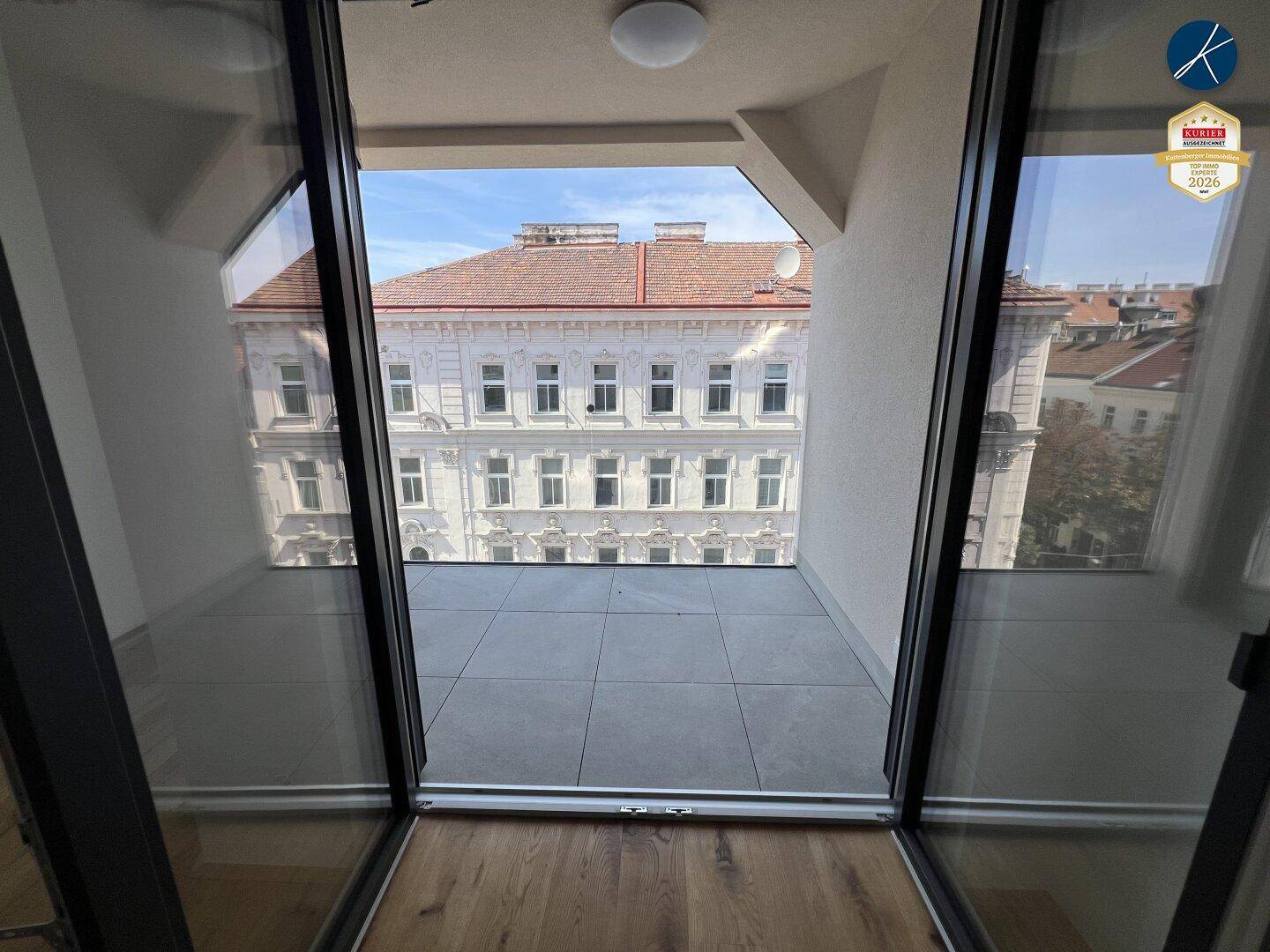 Heller Balkon mit Fliesenboden und Glasbrüstung, bietet einen weiten Stadtblick.