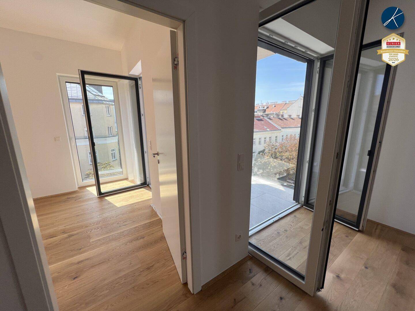 Geräumiger, heller Raum mit Holzboden und großen Fenstern, die viel Licht hereinlassen.