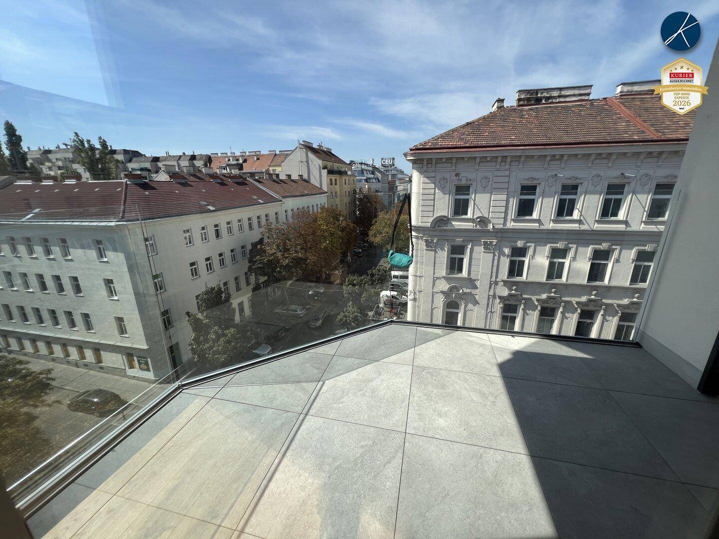 Geräumiger Balkon mit Fliesenboden und Glasgeländer, ideal für entspannte Stunden im Freien.